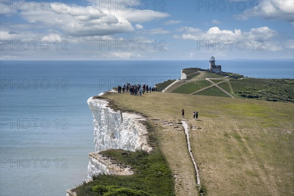 Tourists walking along the chalk cliffs at Beachy Head