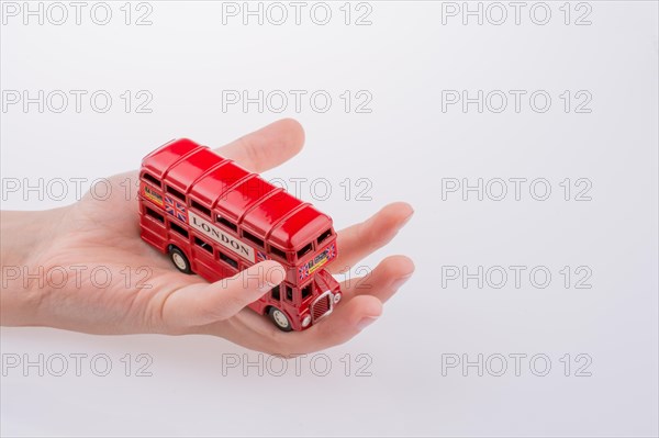 Hand holding a London double decker bus on a white background