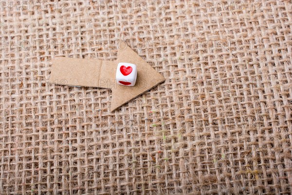 Love cubes on arrow cut out of brown paper on canvas