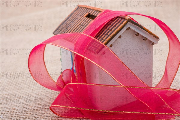 Pink band wrapped around a model house on a brown background