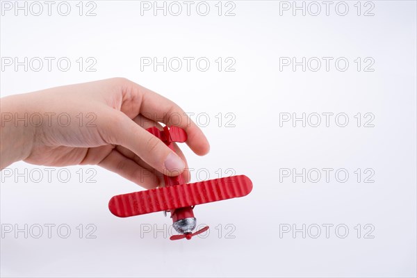 Hand holding a red toy plane on a white background