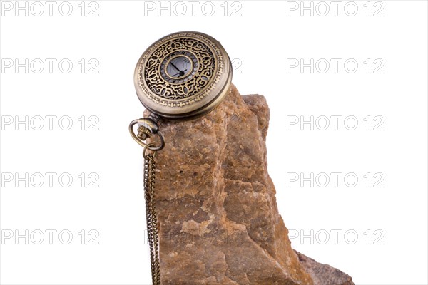 Pocket watch on the top of a rock on a white background