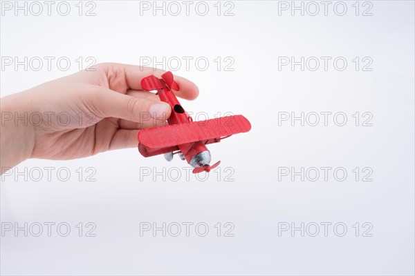 Hand holding a red toy plane on a white background