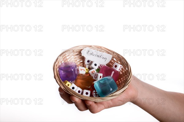 Child hand holding a education written a piece of torn paper in a basket full of letter cubes