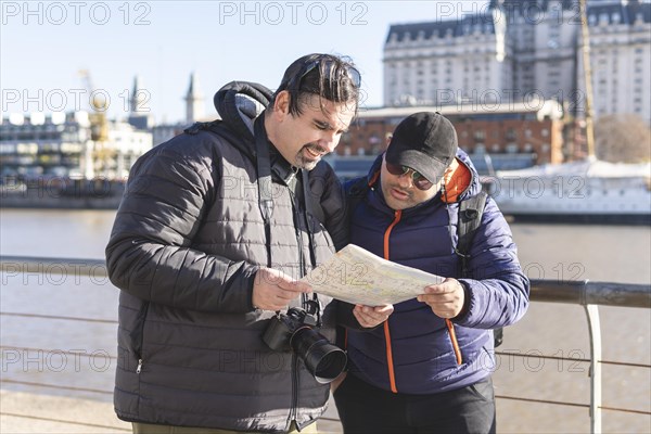 Couple of friends consulting the map while exploring Puerto Madero