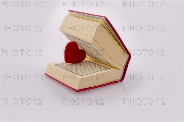 The Holy Quran with a heart on a white background