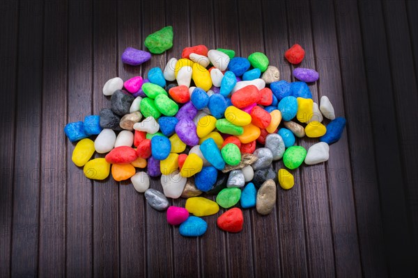 Pile of little colorful pebbles on wooden background