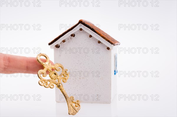 Hand holding a golden key near a house on a white background