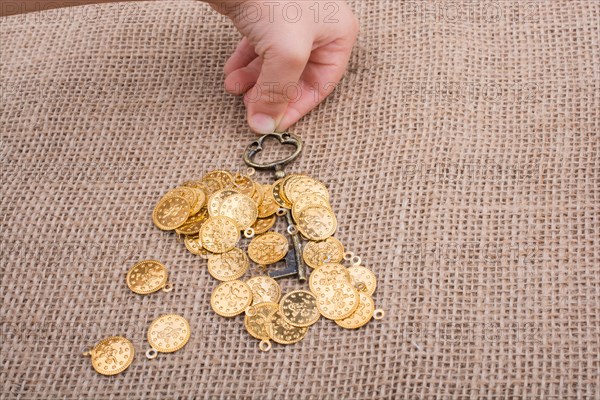 Hand holding a retro styled key over fake gold coins