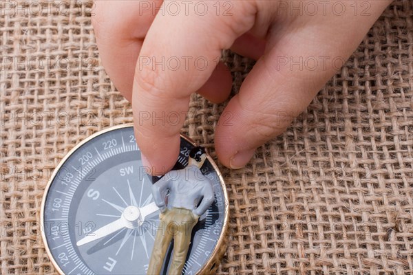 Hand holding a figurine beside a compass