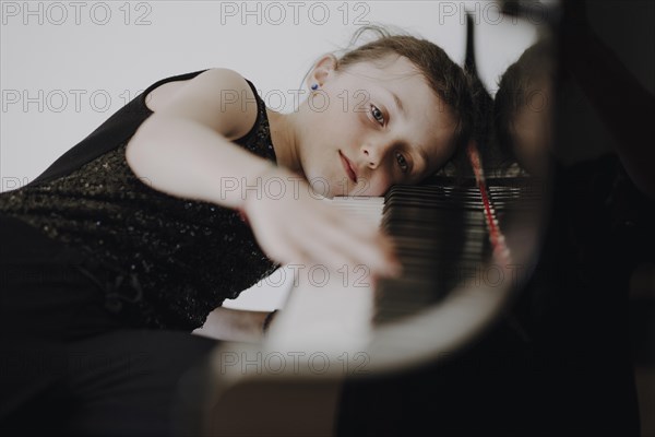 Elegant girl sits at the concert grand and plays the piano