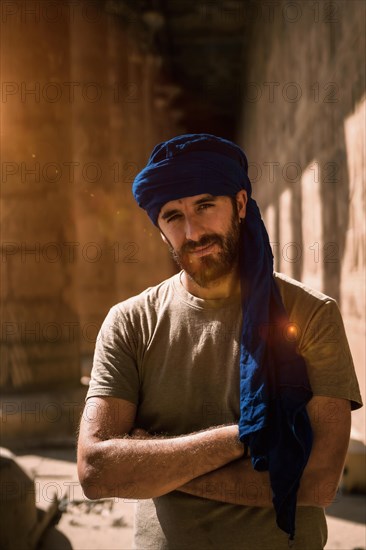 A young tourist in a blue turban visiting the Edfu Temple in the morning near Aswan city. Egypt