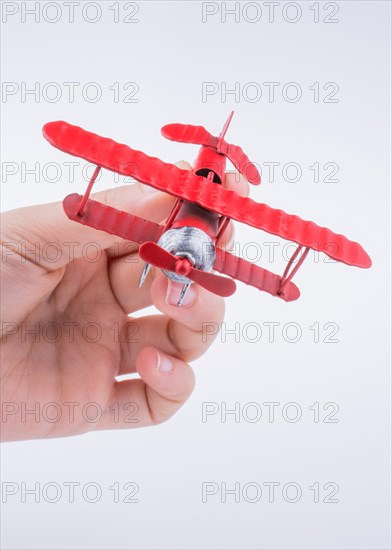 Hand holding a red toy plane on a white background