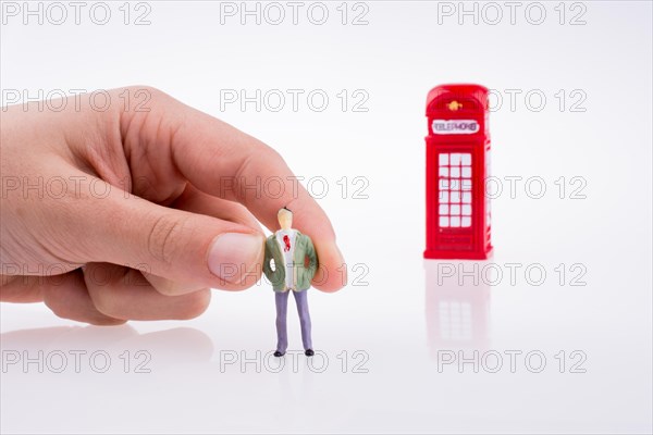 Hand holding a figure near a phone booth on a white background