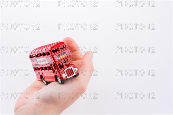 Hand holding a London double decker bus on a white background