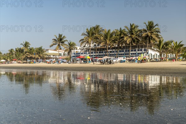 Palm trees on Kotu beach at Paradise Beach Bar and Restaurant reflected in the shallow water at low tide