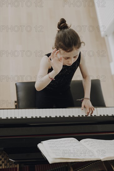 Elegant girl sits at the concert grand and plays the piano