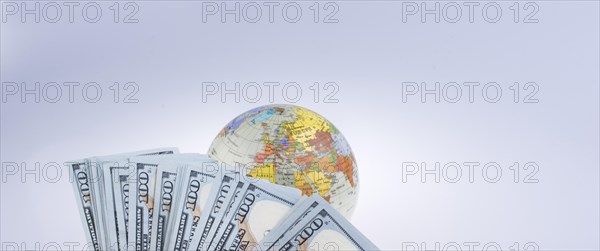 Human hand holding American dollar banknotes by the side of a model globe on white background