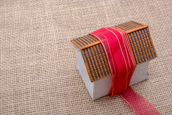 Pink band wrapped around a model house on a brown background