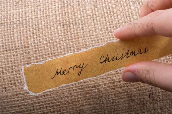 Merry Christmas wording written on a torn paper in hand
