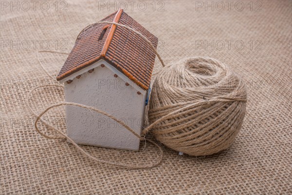 Thread wrapped around a model house on a brown background