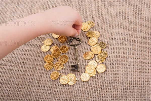 Hand holding a retro styled key over fake gold coins