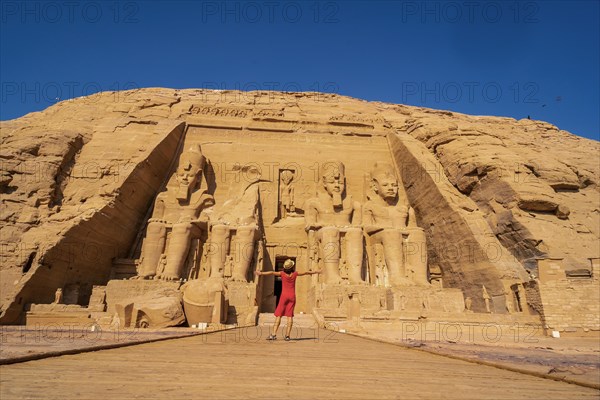 A European tourist in red dress at the Abu Simbel Temple in southern Egypt in Nubia next to Lake Nasser. Temple of Pharaoh Ramses II