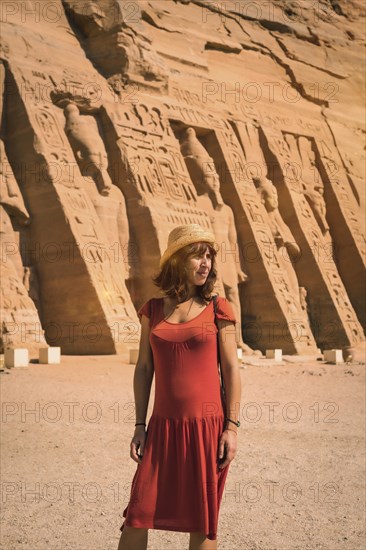A young girl in red dress visiting the Egyptian Temple of Nefertari near Abu Simbel in southern Egypt in Nubia next to Lake Nasser. Temple of Pharaoh Ramses II