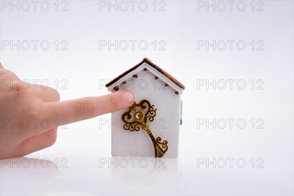 Hand holding a golden key near a house on a white background