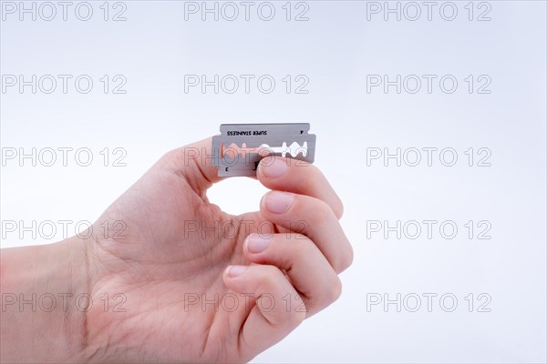 Hand holding a razor blade on a white background