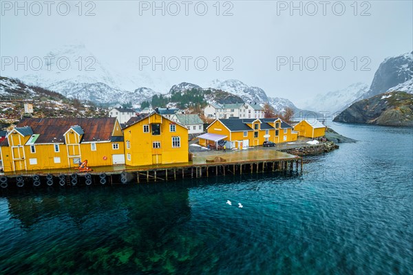 Panorama of Nusfjord authentic fishing village with yellow rorbu houses in Norwegian fjord in winter. Lofoten islands