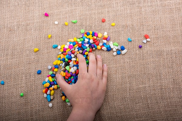 Colorful little pebbles in hand and on canvas ground