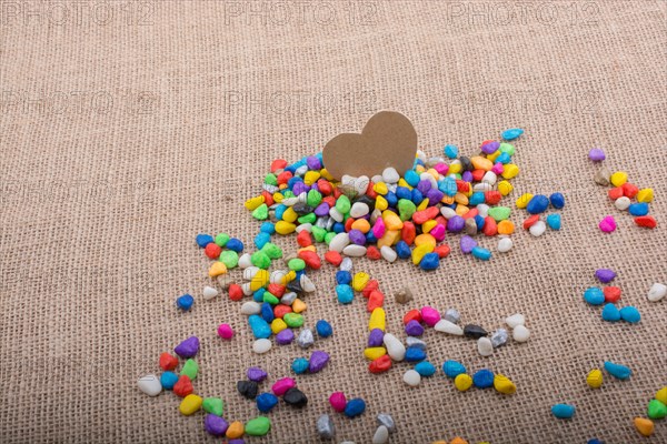 Paper heart amid colorful pebbles on canvas ground