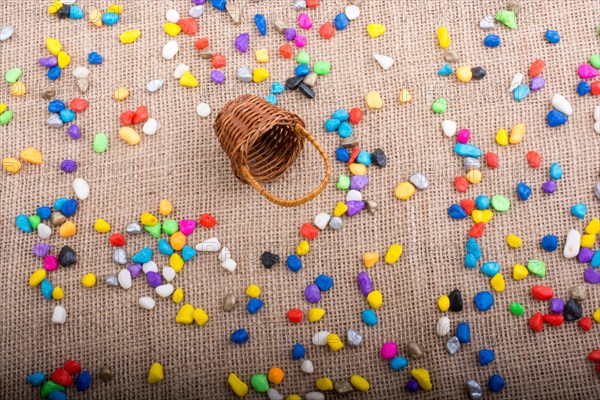 Basket and spilled pebbles on canvas background