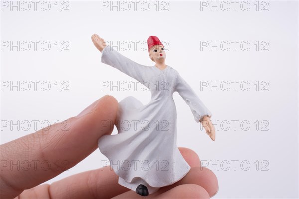 Hand holding a Sufi Dervis on a white background