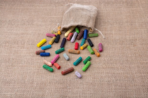 Crayons of various color out of a sack on a canvas