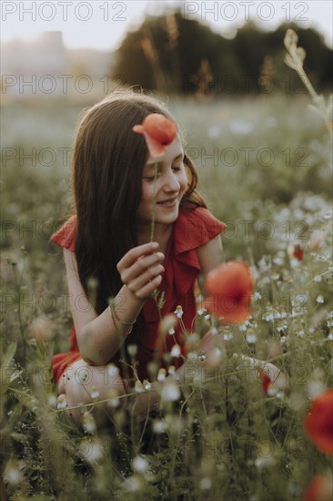 Girl in a red dress in a poppy meadow