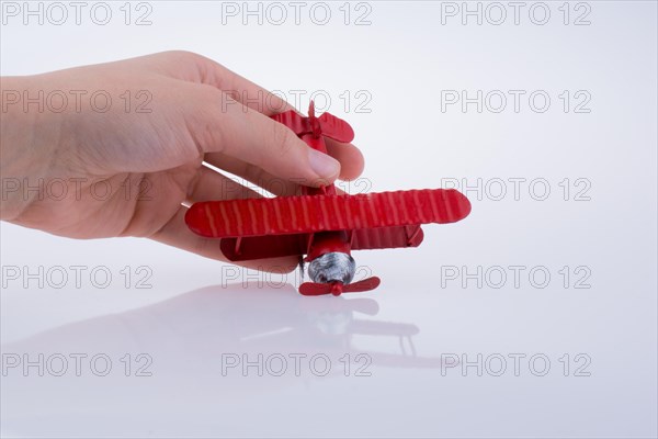 Hand holding a red toy plane on a white background