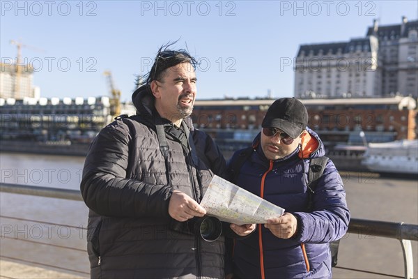 Couple of friends consulting the map while exploring Puerto Madero