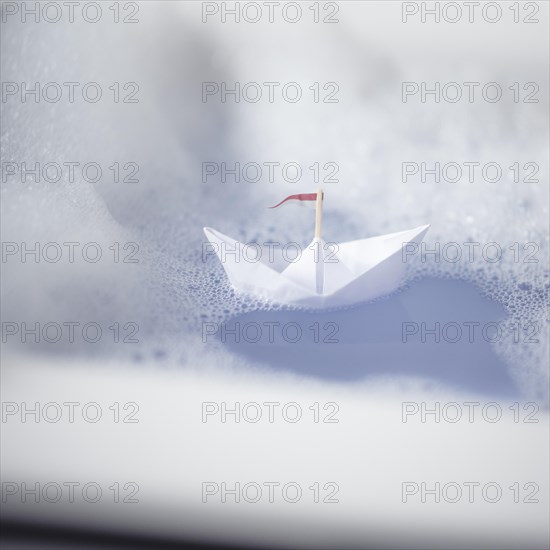 Paper ship in a bathtub with lots of foam