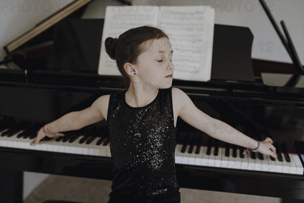 Elegant girl sits at the concert grand and plays the piano