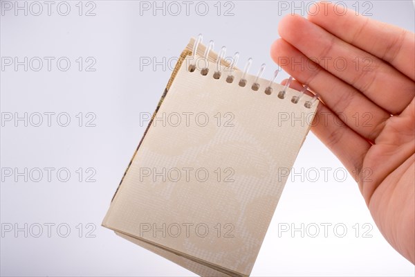 Hand holding Spiral blank notebook on a white background