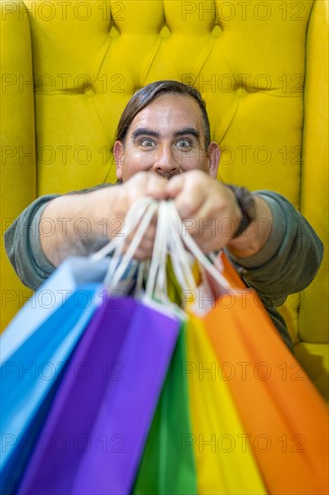 Happy man holding shopping bags on yellow background. Joy of consumption. Purchases