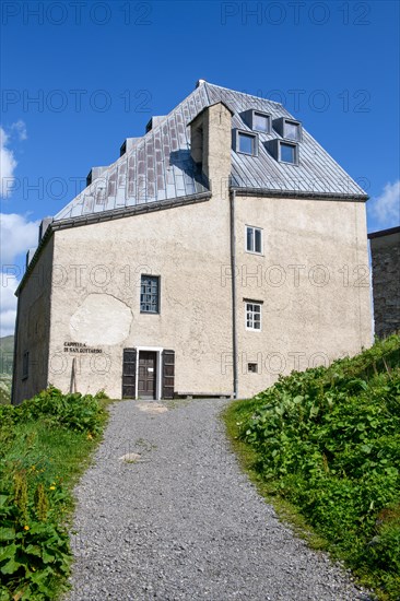 Side view with entrance to chapel in historic hotel accommodation Ospizio San Gottardo Sankt Gotthard Hospice with historic buildings from year 1237 13th century on 2091 metres high Gotthard Pass