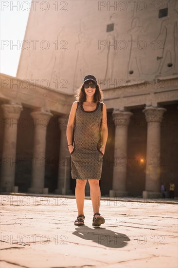 A young tourist wearing a cap visiting the Edfu Temple at sunrise in Aswan. Egypt