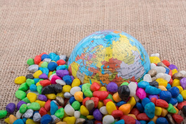 Model globe placed amid colorful pebbles