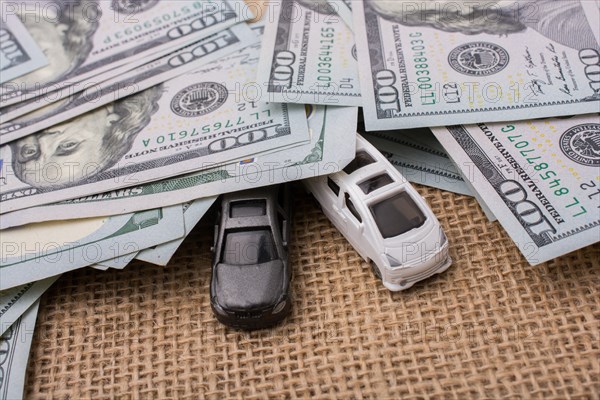 Model cars covered by US dollar banknotes spread on ground