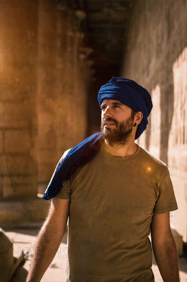 Young man in blue turban walking on the columns of the Edfu Temple near the city of Aswan. Egypt