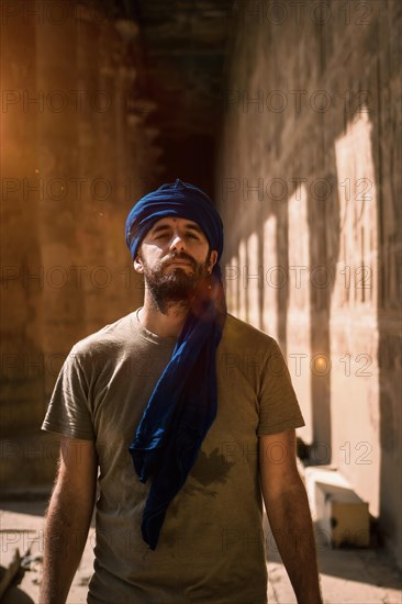 A young tourist in a blue turban visiting the Edfu Temple in the morning near Aswan city. Egypt