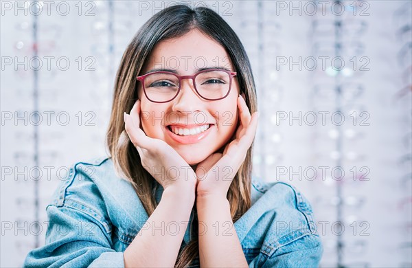 Portrait of beautiful girl modeling glasses in an optical store. Happy girl modeling glasses in an optical lens store